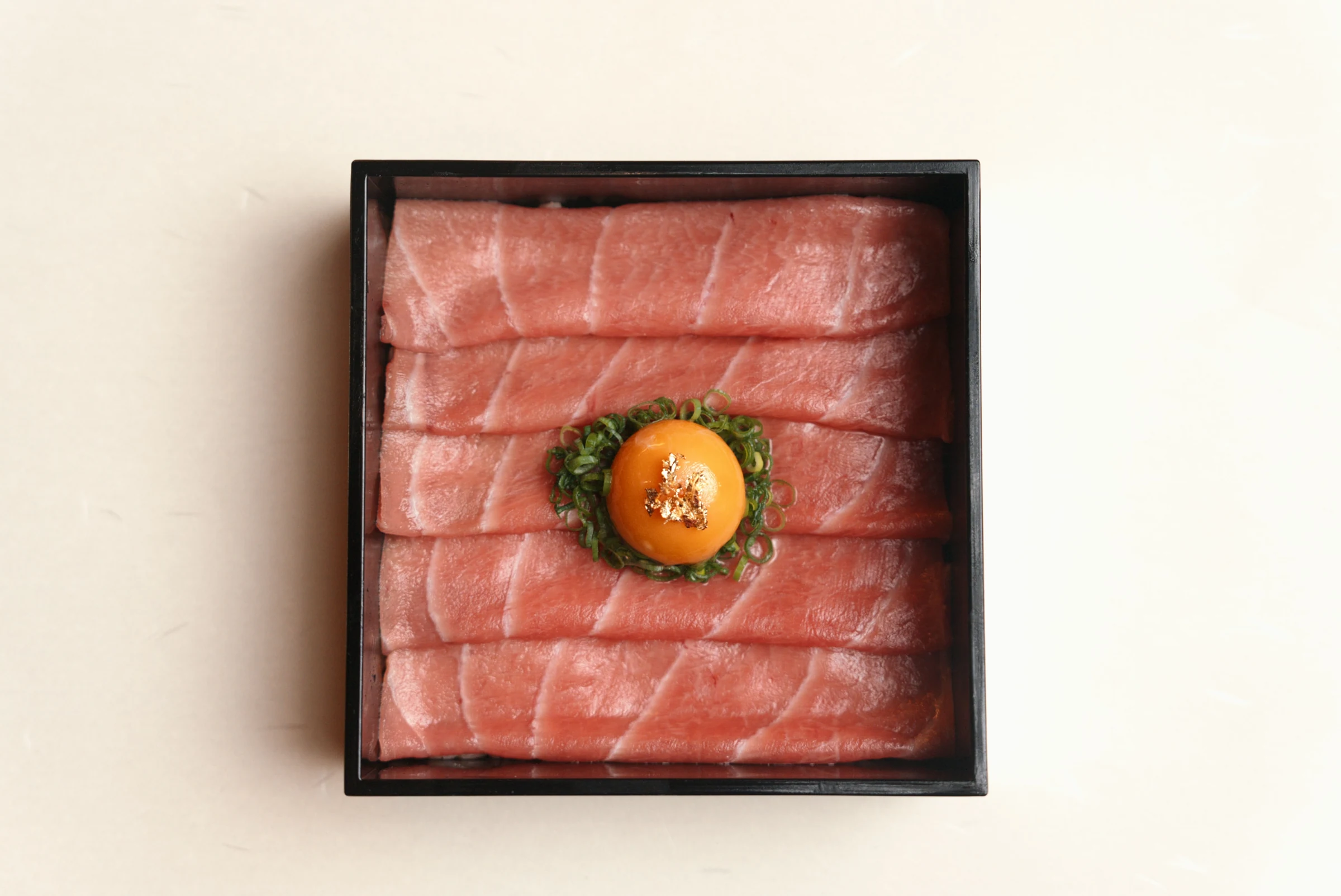 薄切りの本マグロの大トロに卵黄とねぎ、金箔を添えた本マグロ 日の出重